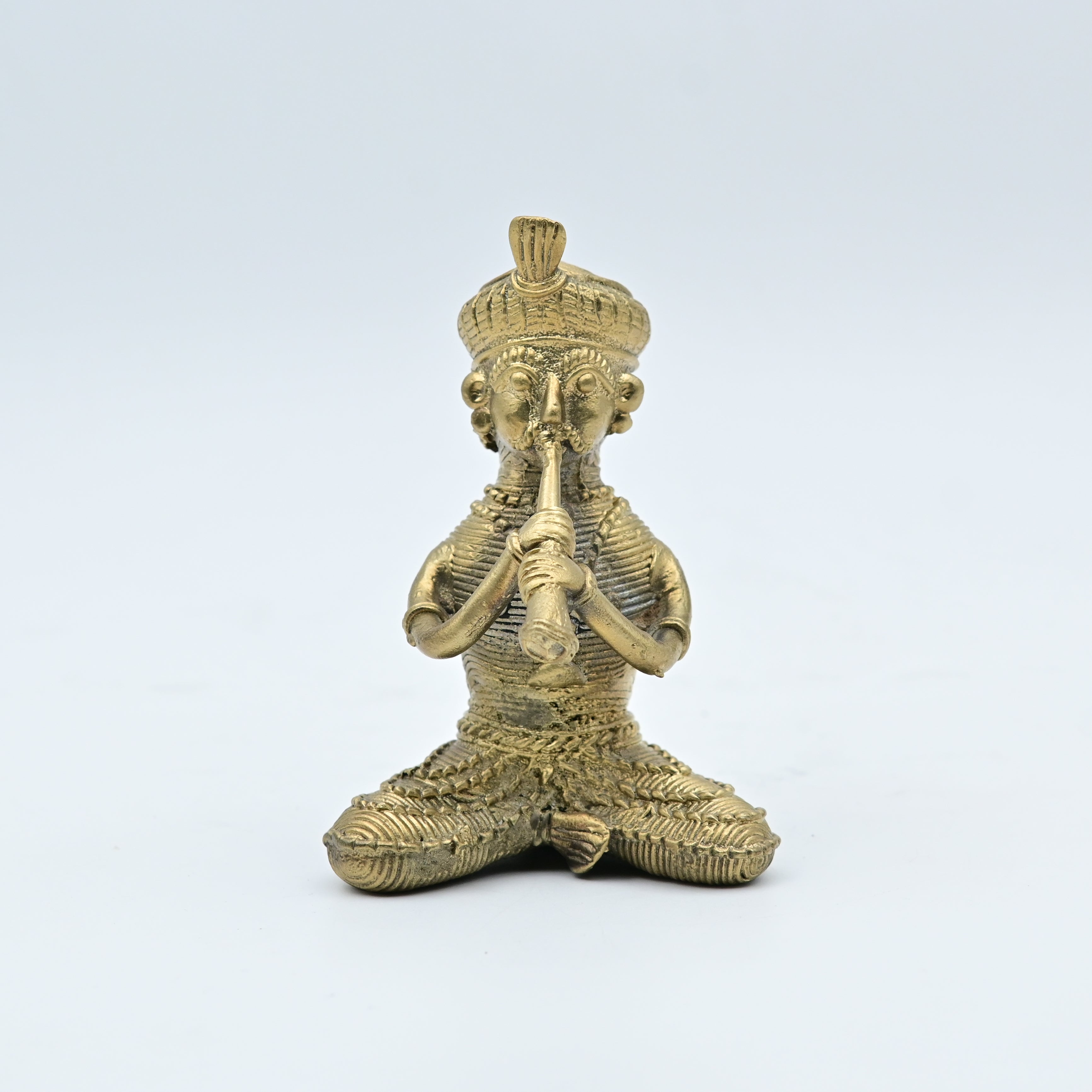 This item is a handcrafted brass figurine depicting a tribal folk musician playing a traditional instrument, often categorized as Dhokra art from India. 