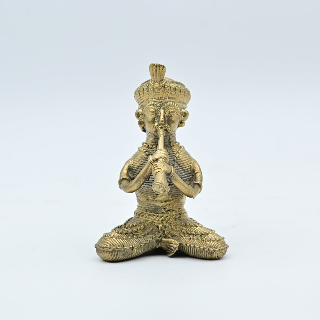 This item is a handcrafted brass figurine depicting a tribal folk musician playing a traditional instrument, often categorized as Dhokra art from India. 
