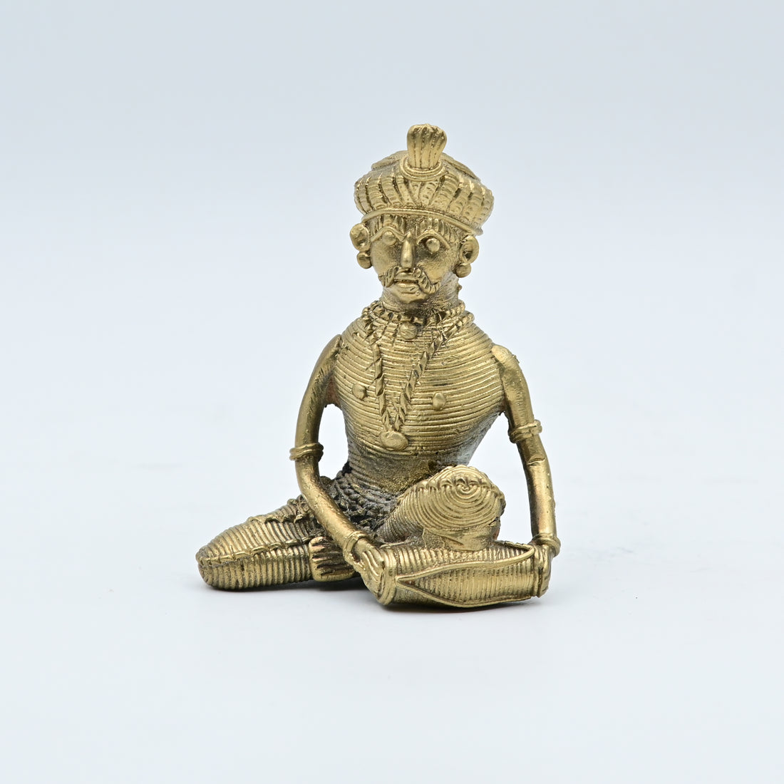 This item is a Dhokra art brass statue depicting a tribal musician playing a drum. 