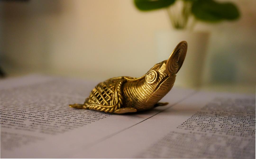 A brass coin catching sea turtle statue with an antique look.