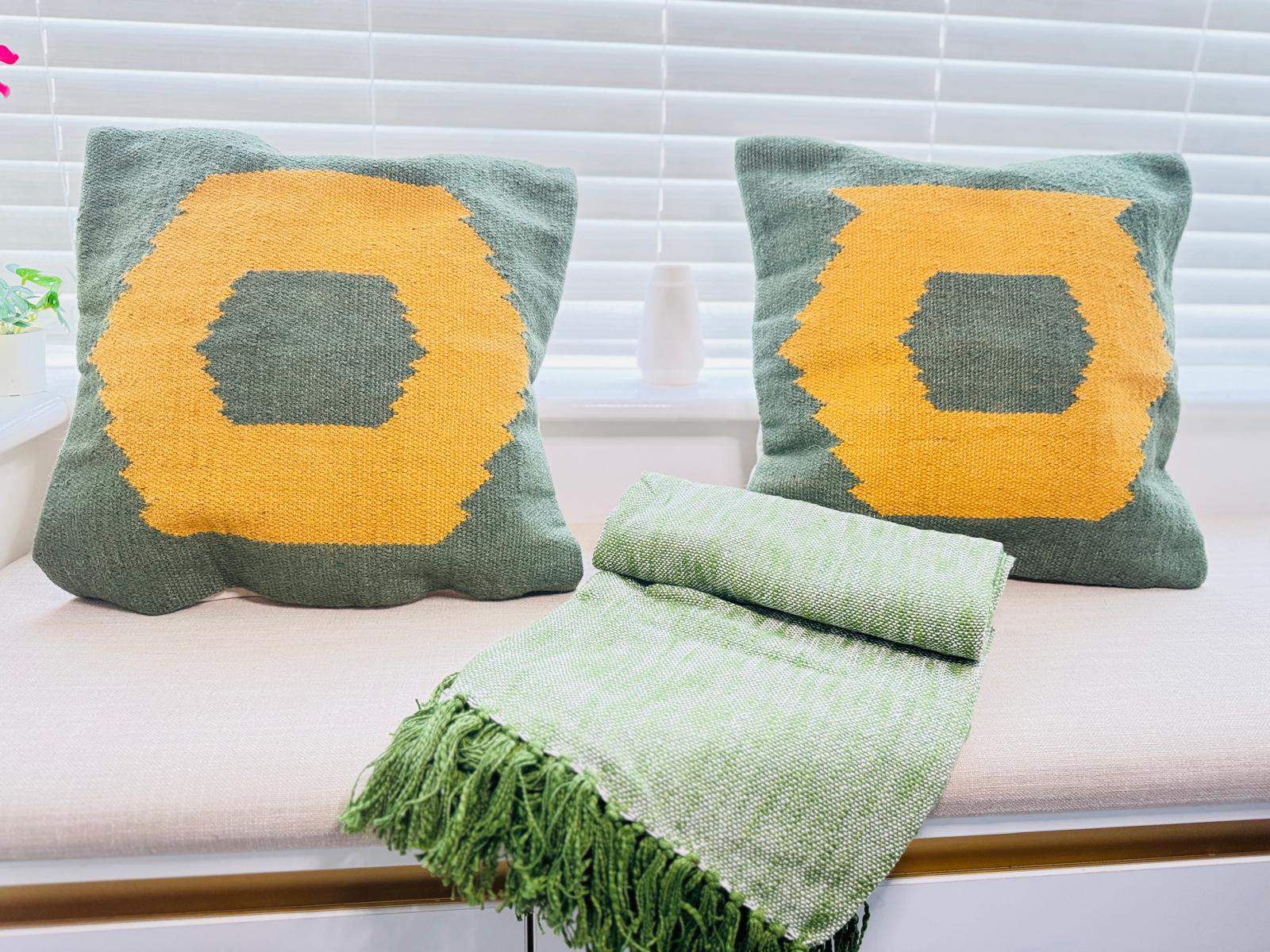 Two green pillows with yellow centers and a matching green blanket on a white couch.