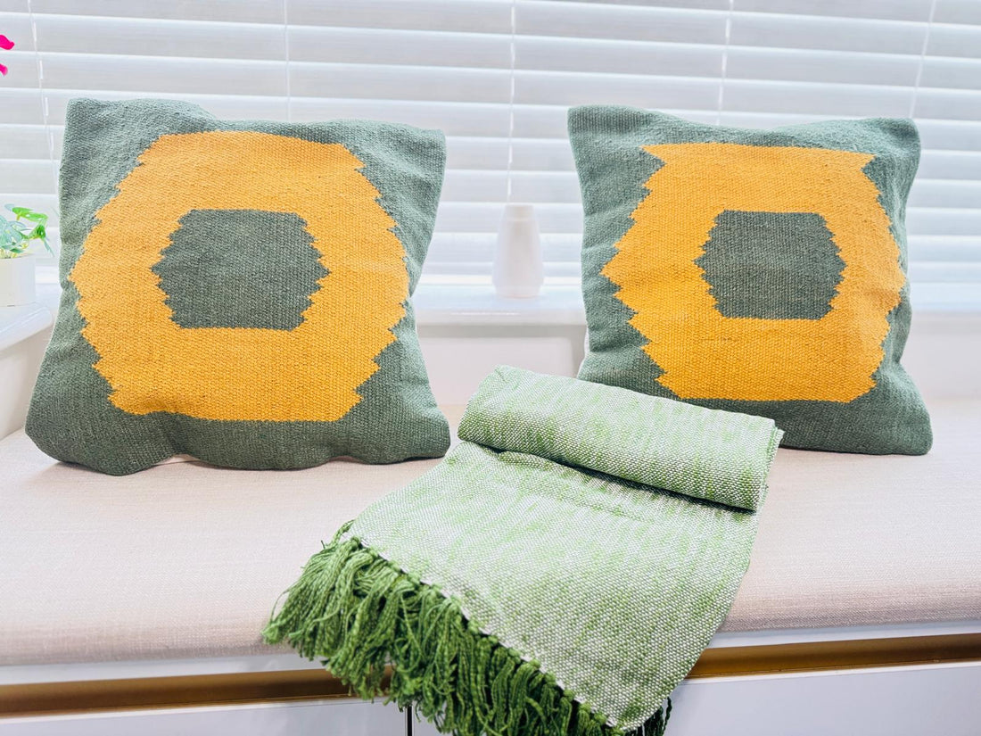 Two green pillows with yellow centers and a matching green blanket on a white couch.