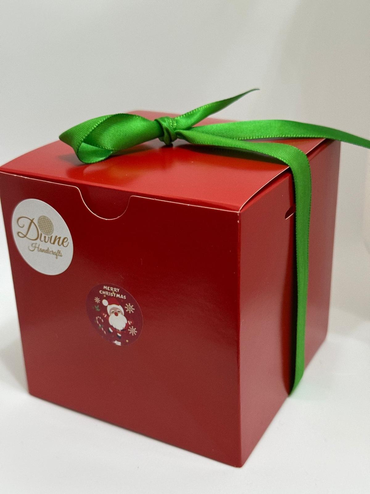 A red gift box with a green ribbon, featuring a logo and a Christmas-themed decoration on the front, containing animal figurines.