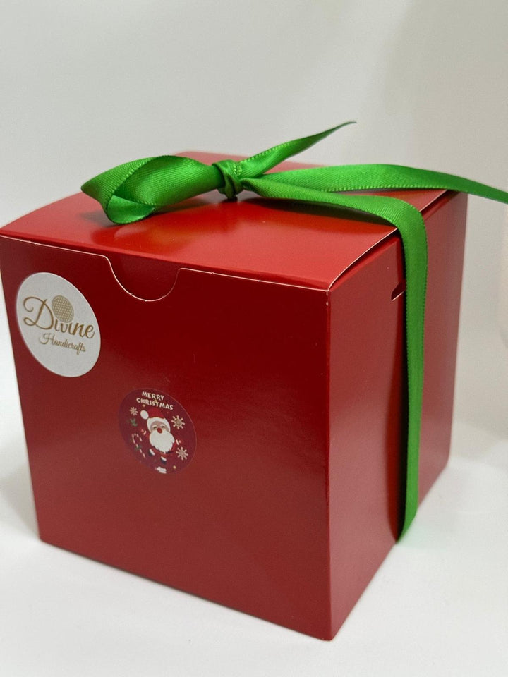 A red gift box with a green ribbon, featuring a logo and a Christmas-themed decoration on the front, containing animal figurines.