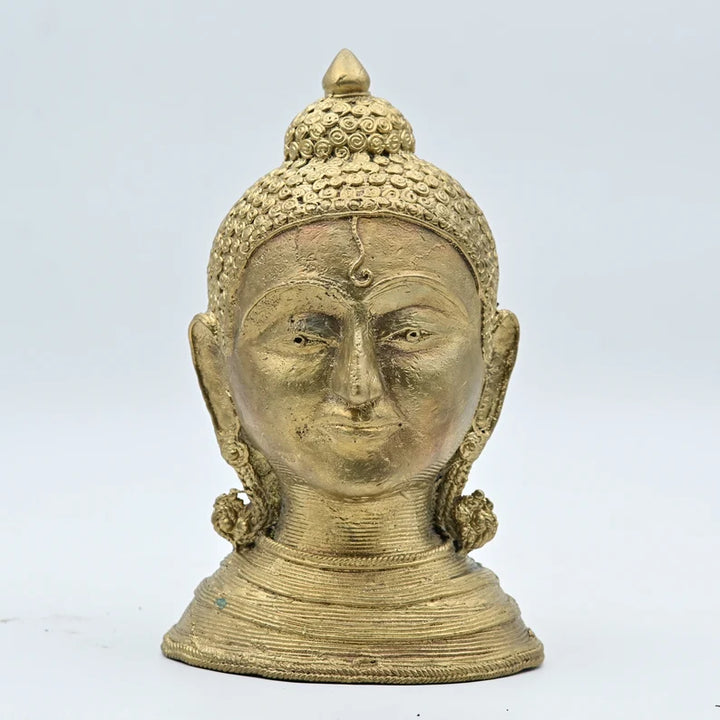 A brass statue of the Buddha with a serene expression, featuring intricate carvings and a metallic finish.