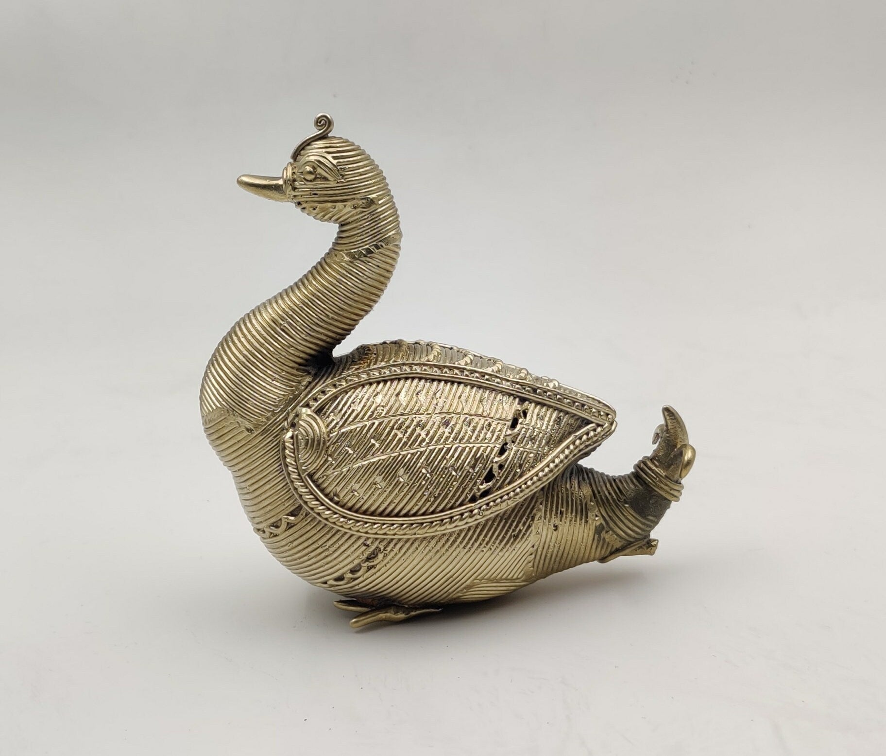 A Dhokra metal statue of an Indian swan with a gold hue.