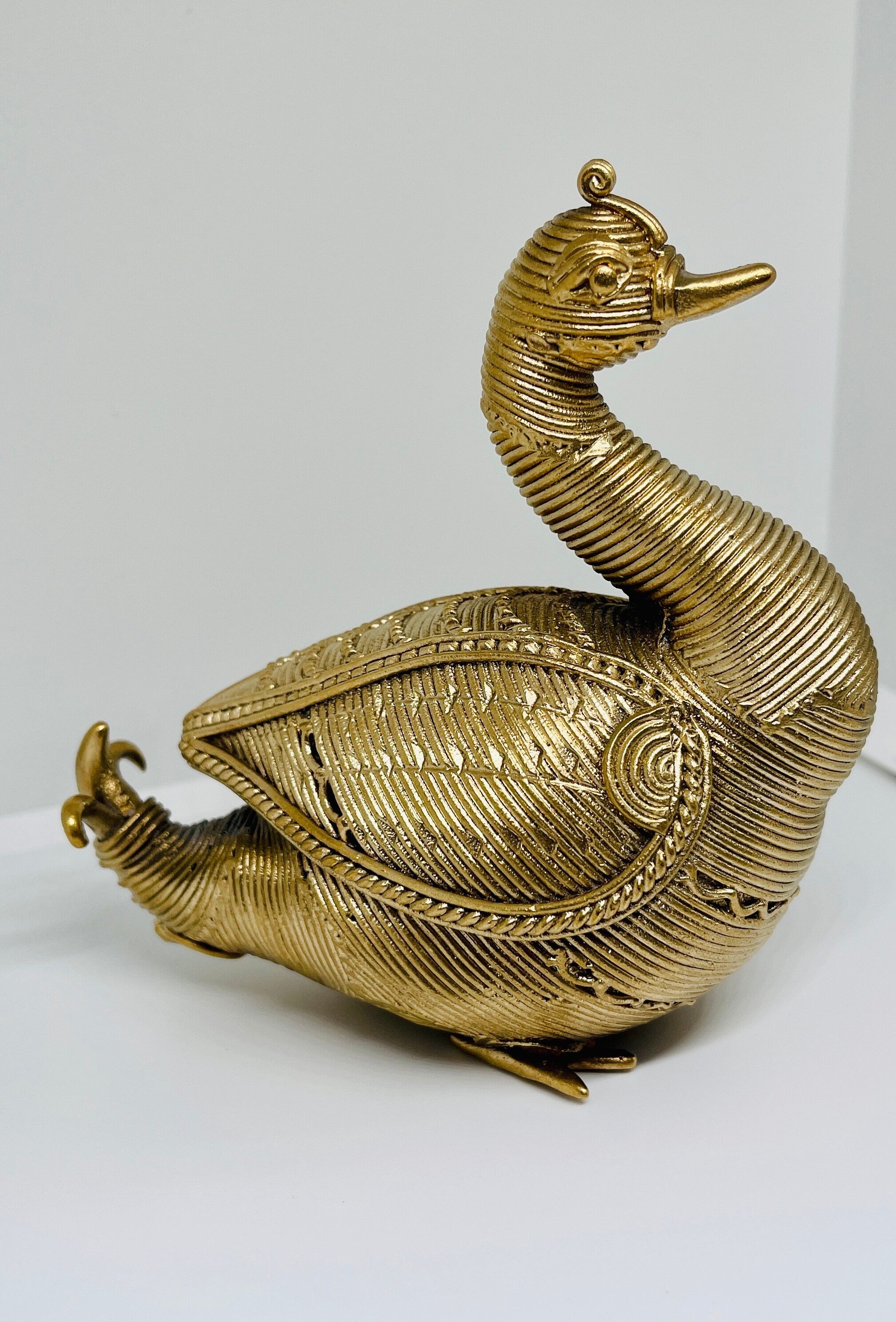A Dhokra metal statue of an Indian swan with a gold hue.