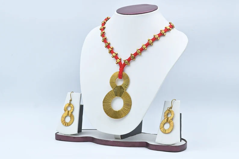 A woman sitting outdoors wearing a white dress and the Lucky Eight Tribal Necklace along with matching earrings.