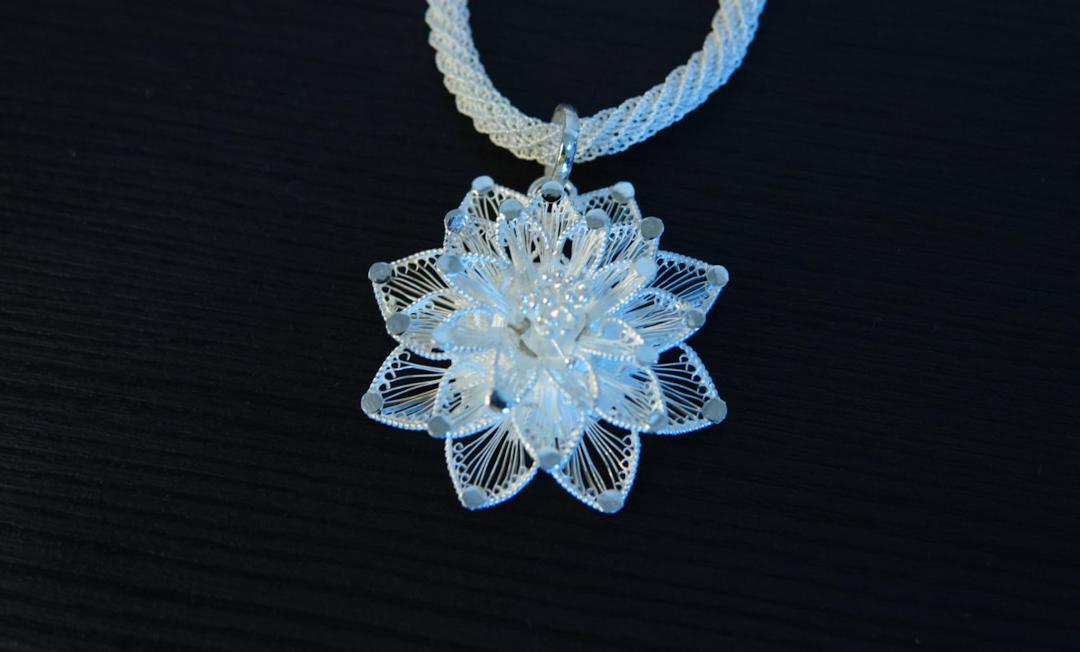 Intricate silver filigree flower pendant on a braided chain