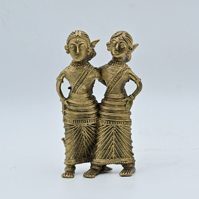 A bronze and brass statue of a tribal dancing couple with intricate details and an antique gold finish.